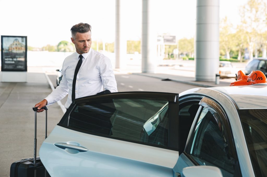 Handsome mature businessman getting in taxi