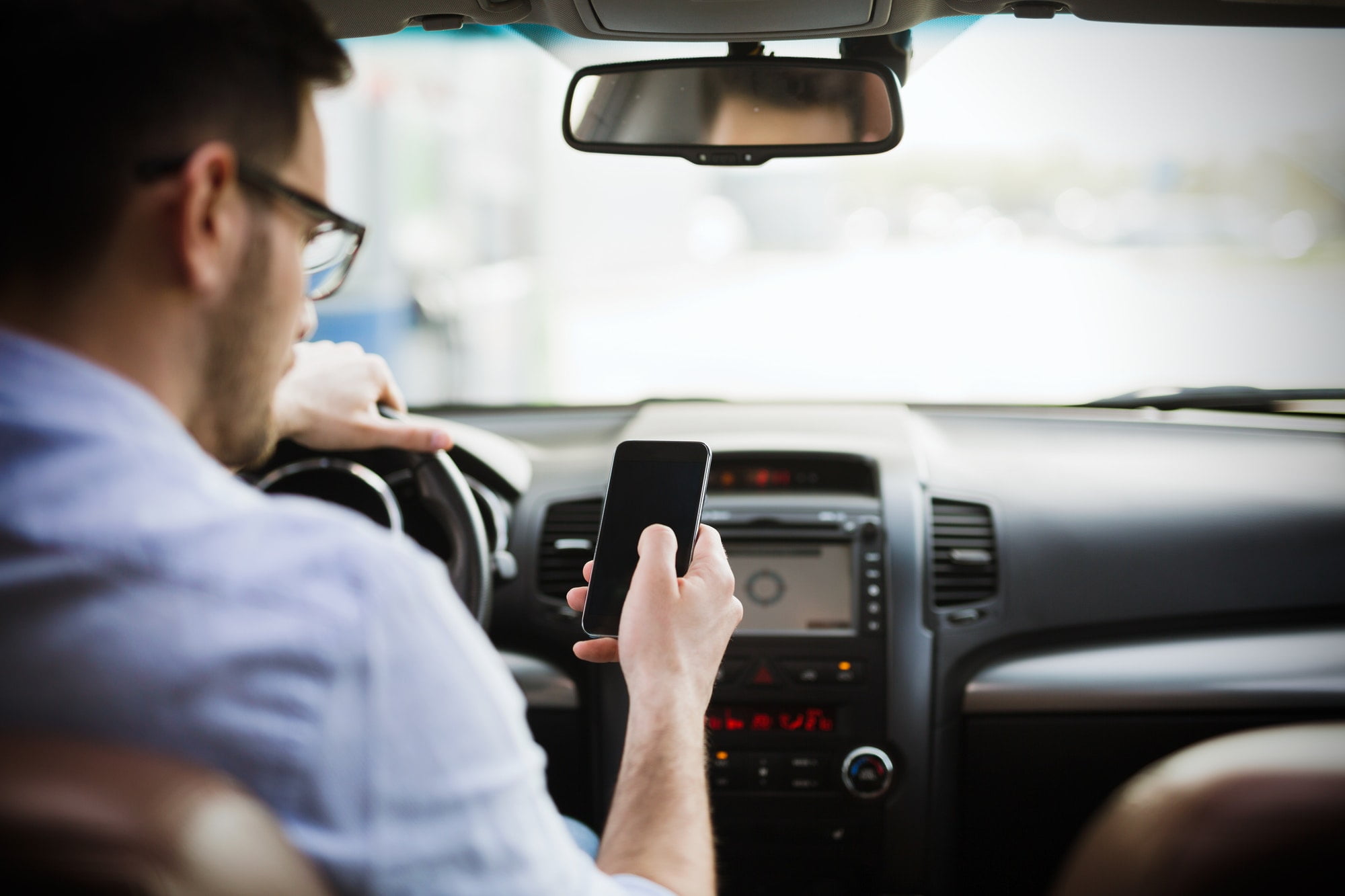 Geschäftsmann ignoriert Sicherheit und SMS am Mobiltelefon während der Fahrt